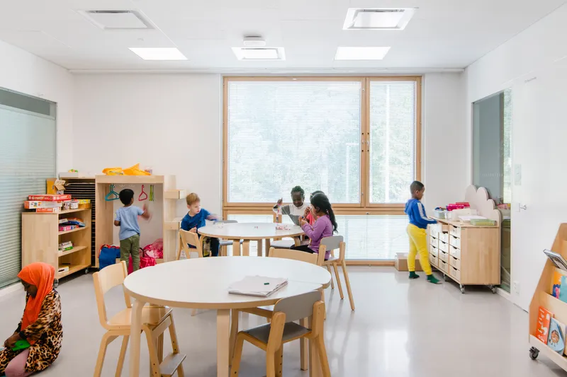 White classroom with timber-framed window, ceiling skylights and children working at low tables
