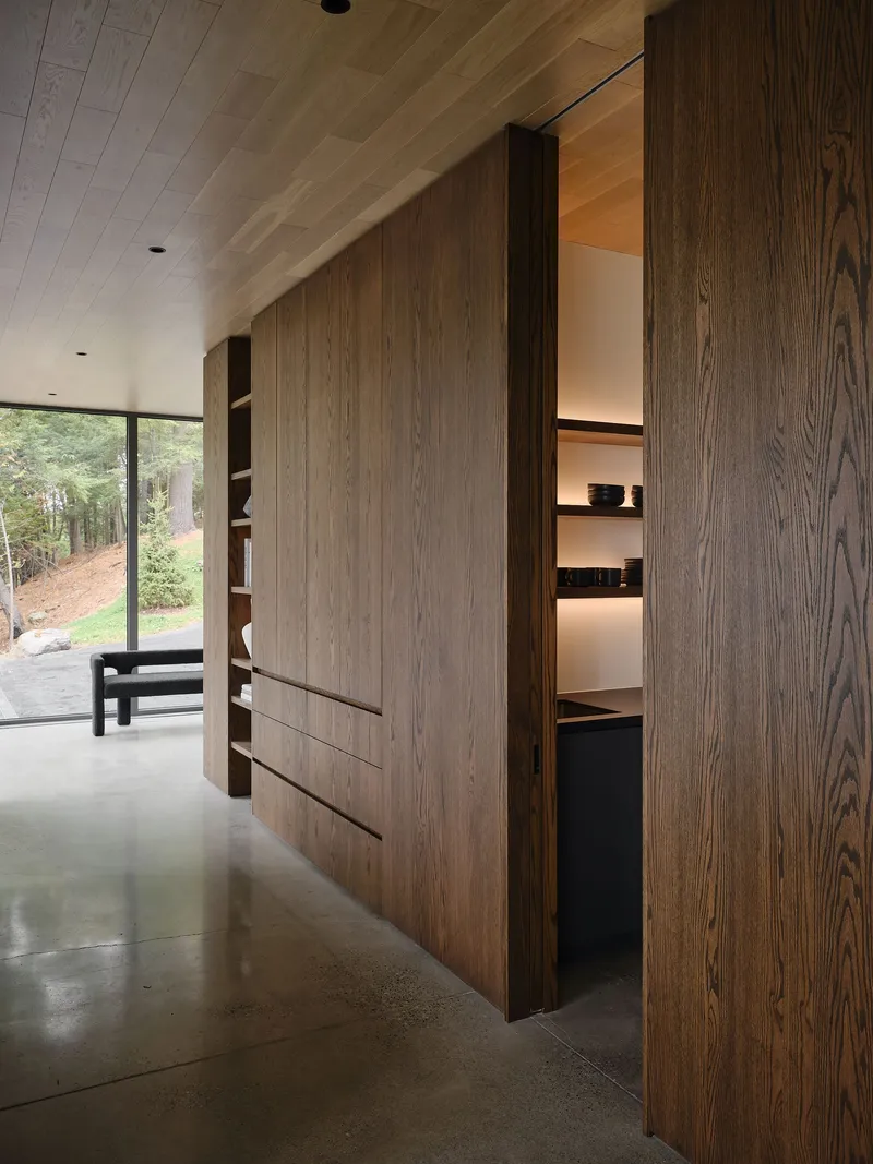 Built-in timber cabinetry with sliding panels and illuminated shelving along a polished concrete floor