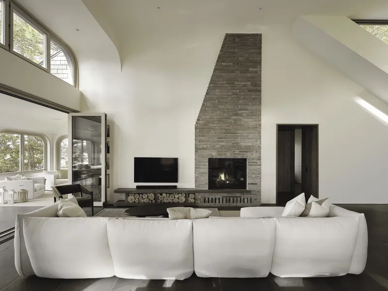 Vaulted living room with stacked brick fireplace, arched clerestory windows, and firewood storage niche