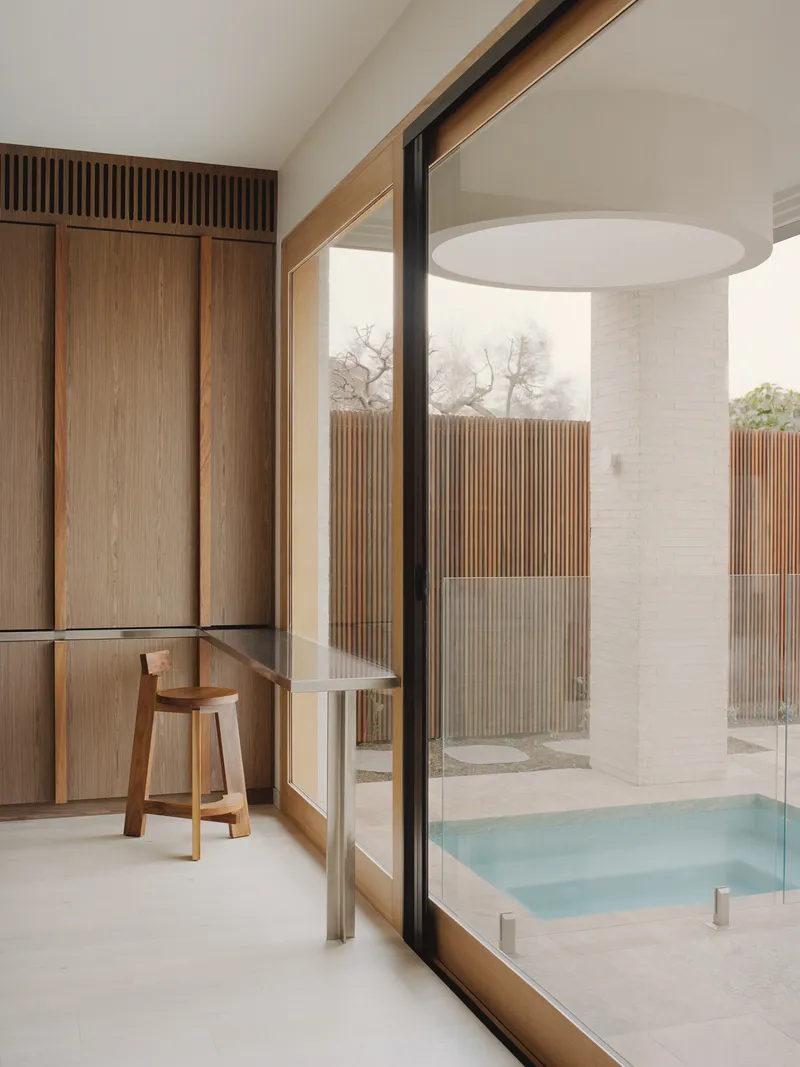 Interior view through timber-framed glazing to courtyard bathing space with vertical wood slat screens