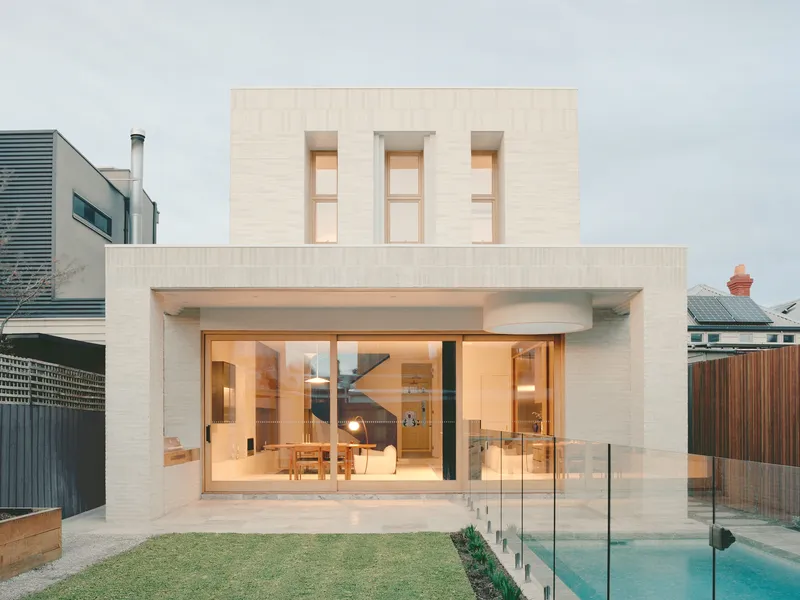 Rear facade with pale brick, recessed glazed doors, three upper windows, and adjacent pool with glass balustrade
