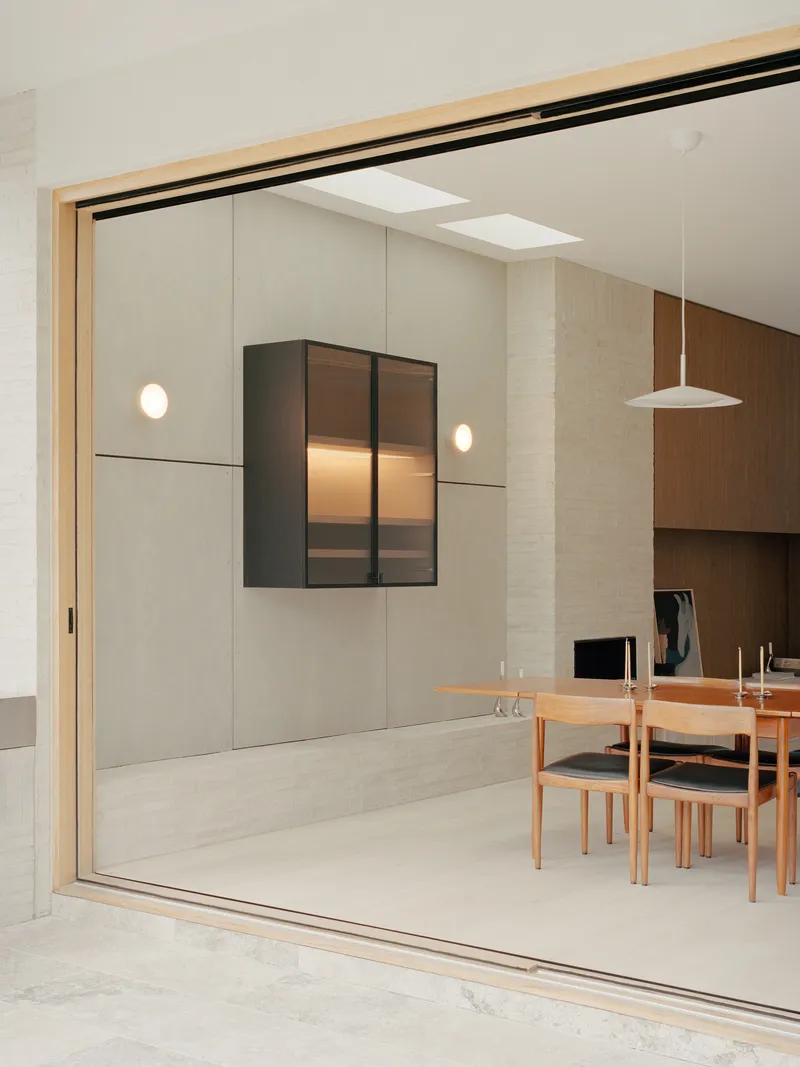 Dining room with timber table viewed through sliding glass doors and overhead skylights
