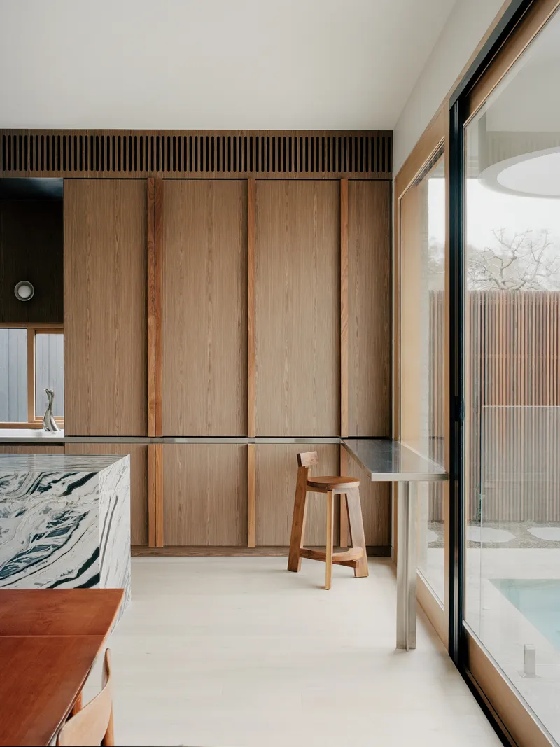 Bedroom with floor-to-ceiling timber wardrobes and glazed door opening to slatted timber screening outside