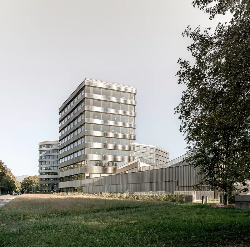 Multi-storey tower with louvered facade rising above a horizontal ribbed base in afternoon light