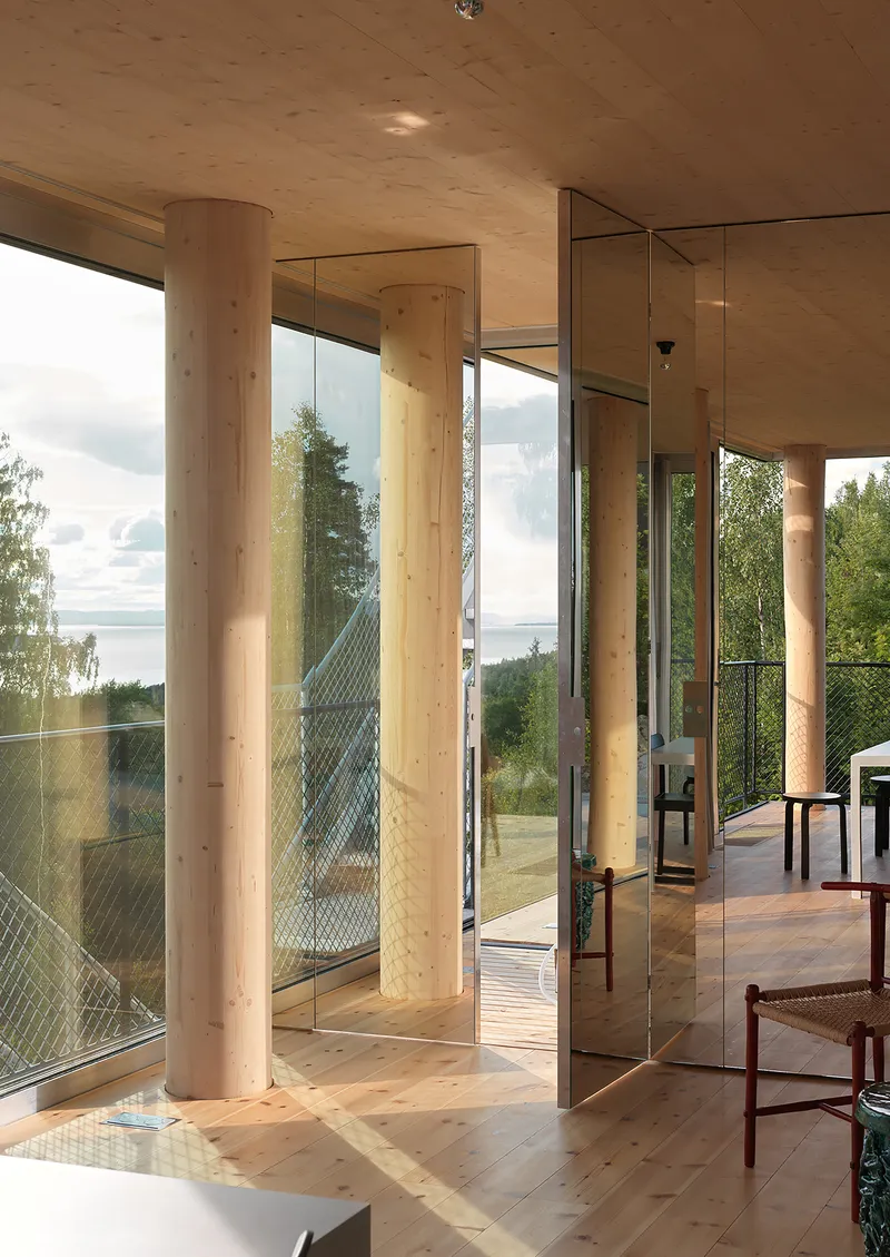 Timber columns and glass walls reflecting the angled roof element in warm afternoon light