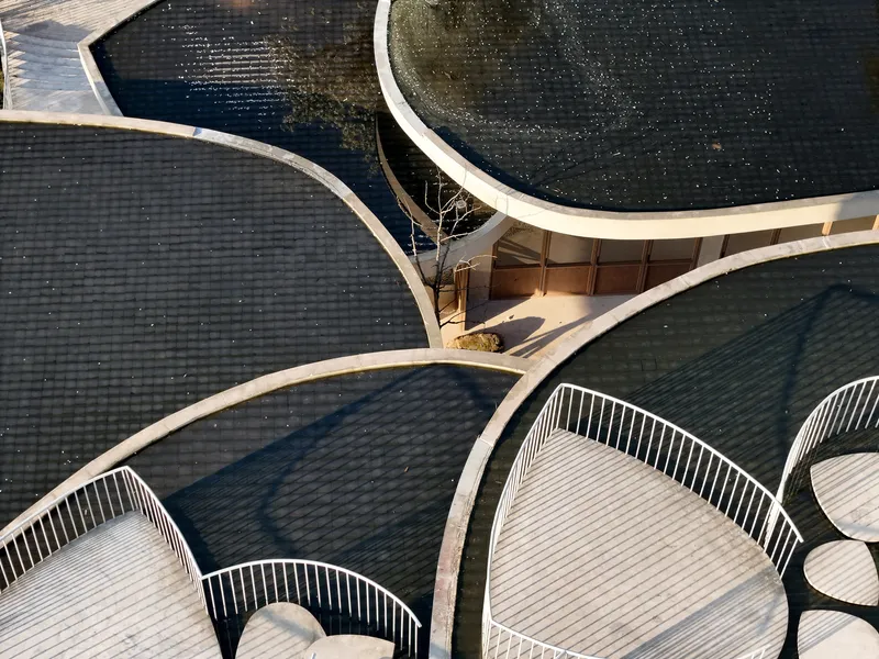 Overhead view of interlocking curved roof terraces with tiled surfaces and white metal railings