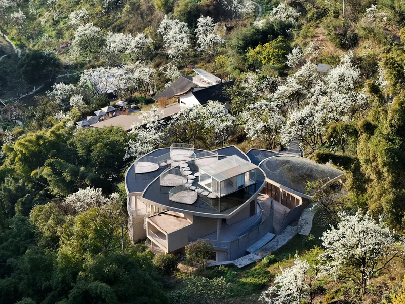 Aerial view of the cloverleaf-shaped roof structure nestled among flowering trees and dense vegetation