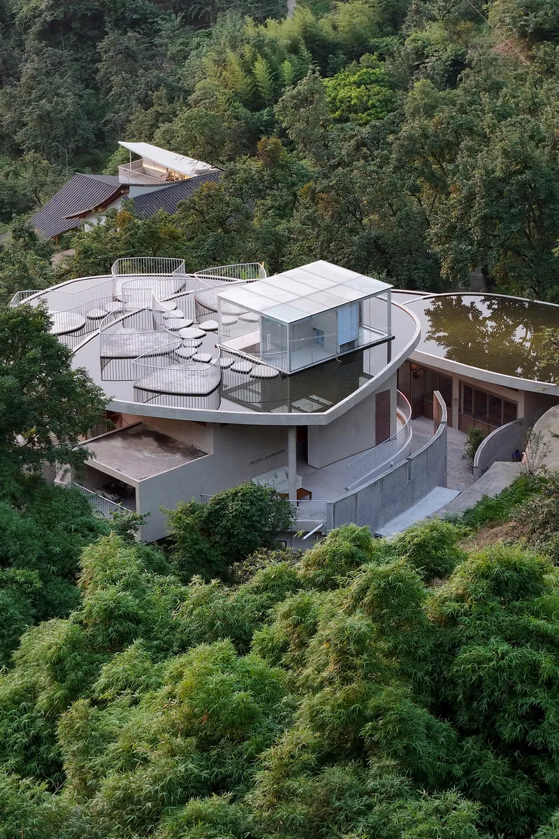 Elevated view showing the layered roof forms with ribbed surfaces and curved balconies descending the hillside