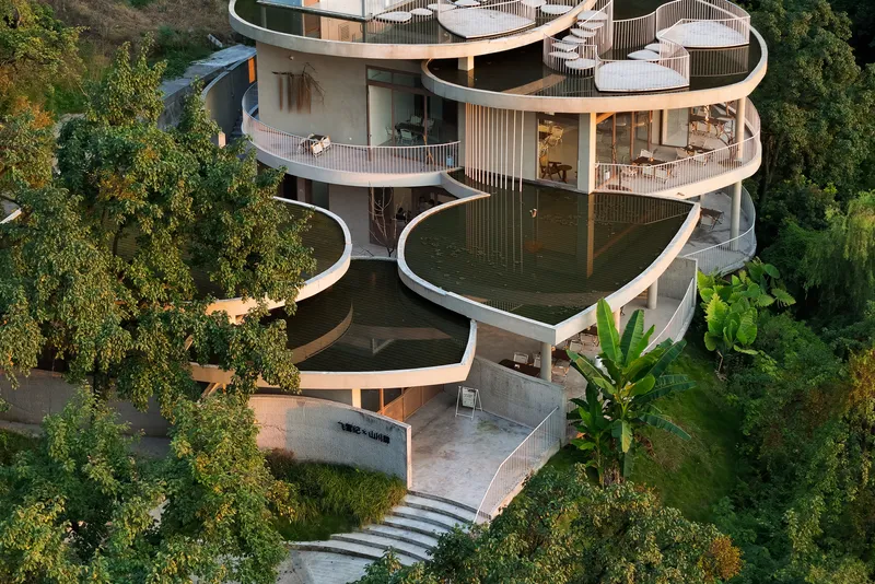 Close view of the undulating balconies with vertical railings and concrete terrace leading to entry steps