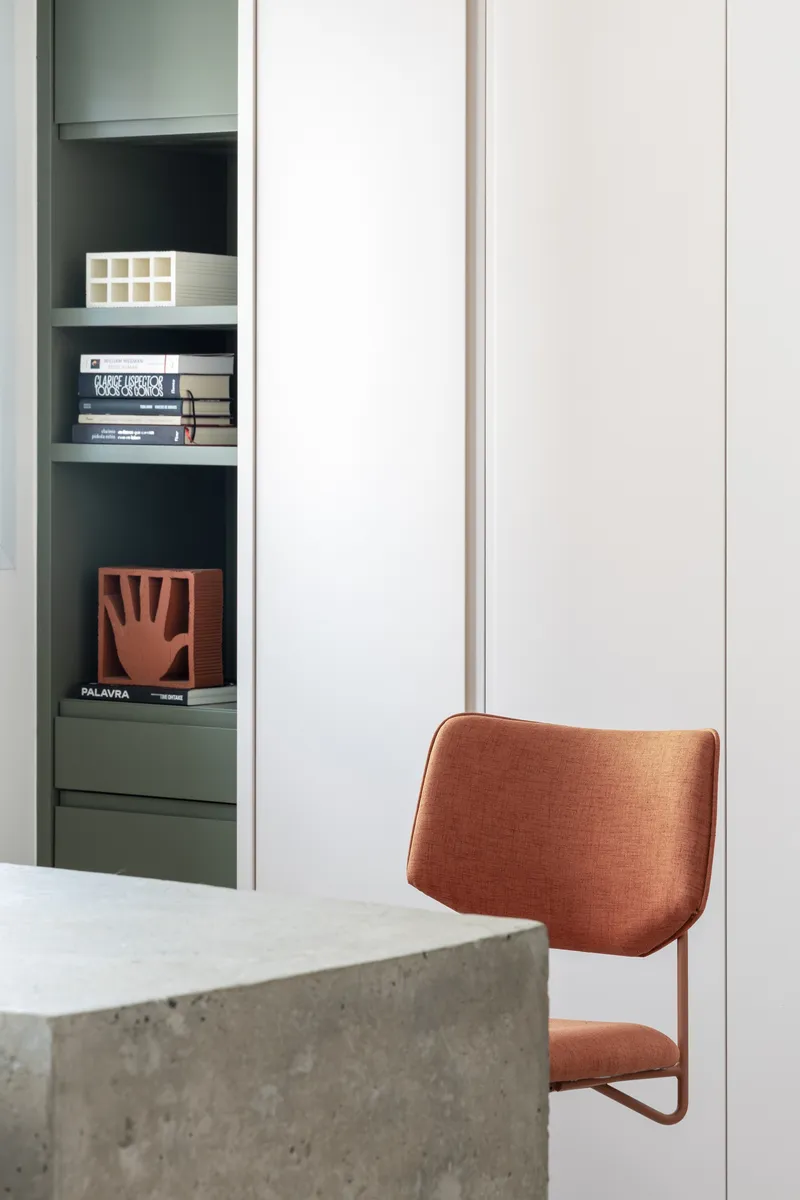 Built-in shelving unit with green-painted interior next to concrete column edge and upholstered chair