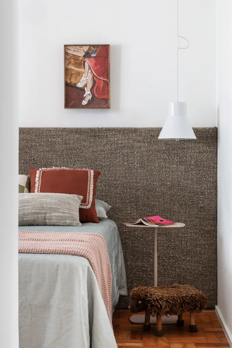 Bedroom with woven textile headboard panel and painting above the bed