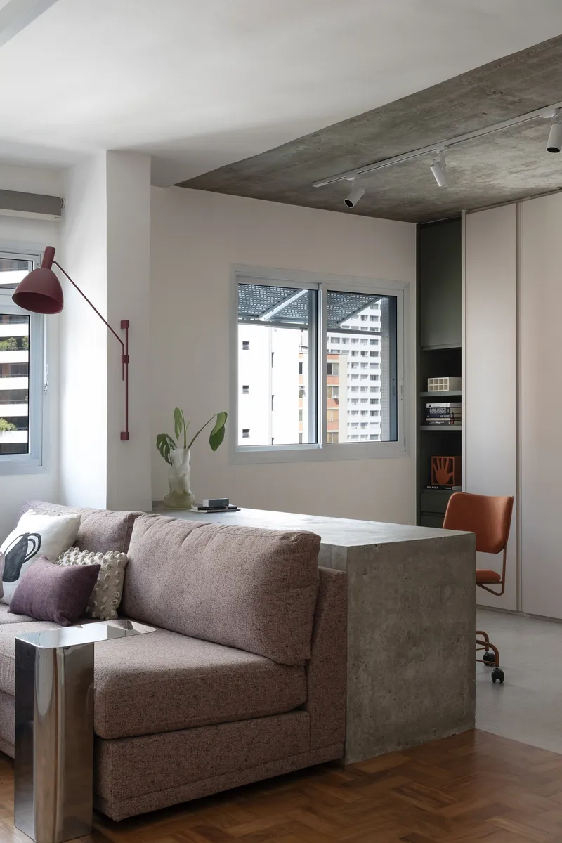 Living room corner with concrete partition wall and window overlooking neighboring buildings