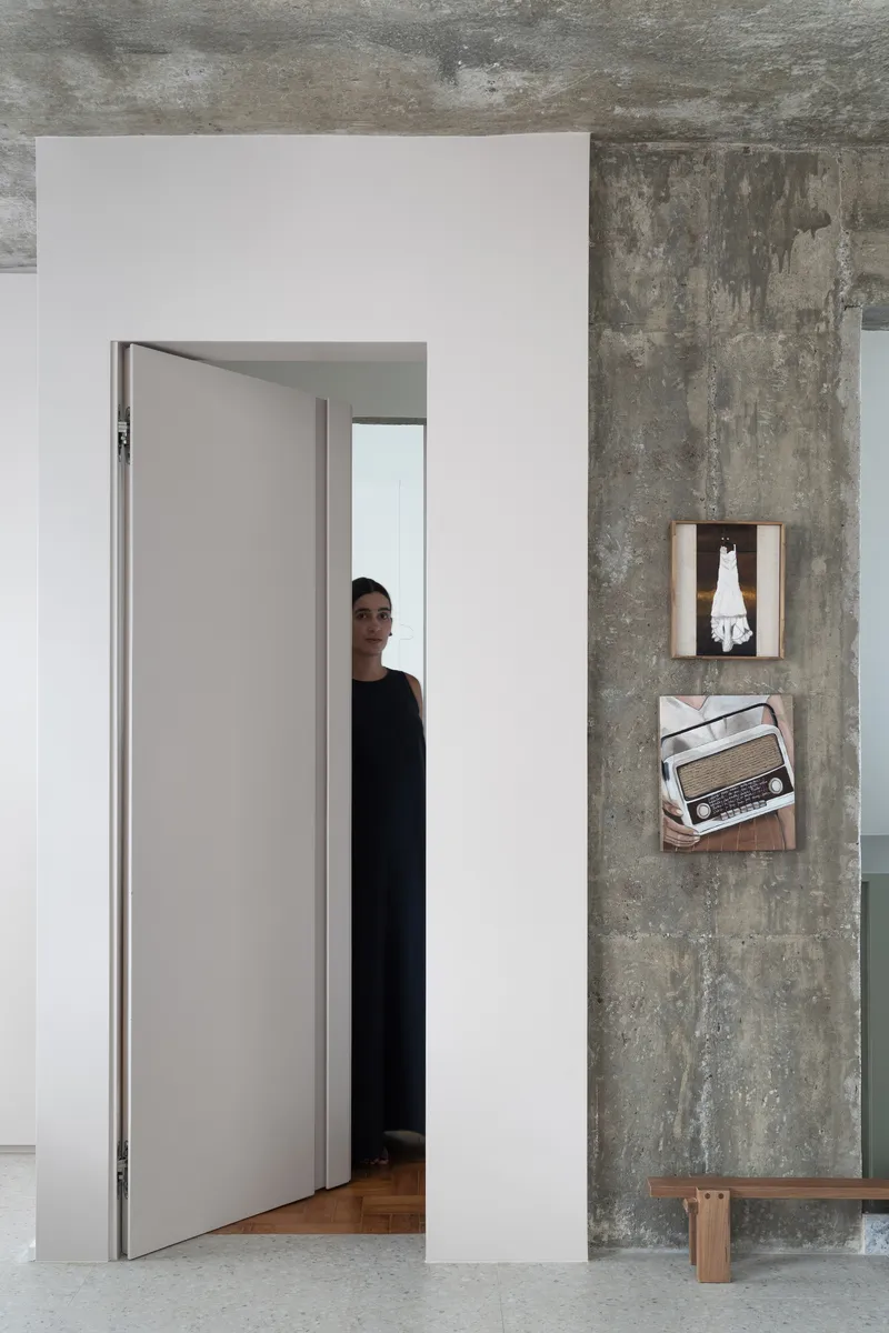 Doorway framed by white walls and exposed concrete ceiling with a person visible beyond