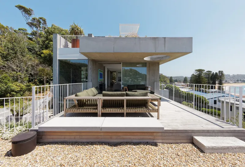 Roof deck with timber seating and white railing overlooking coastal vegetation and distant bay