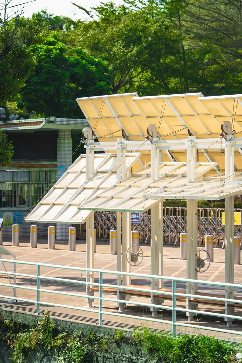 Tilted canopy structure with translucent panels and exposed white steel supports near bike parking