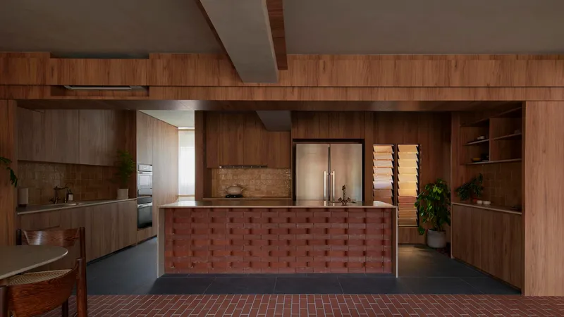 Kitchen island clad in checkered red brick tile beneath timber cabinetry and angled ceiling
