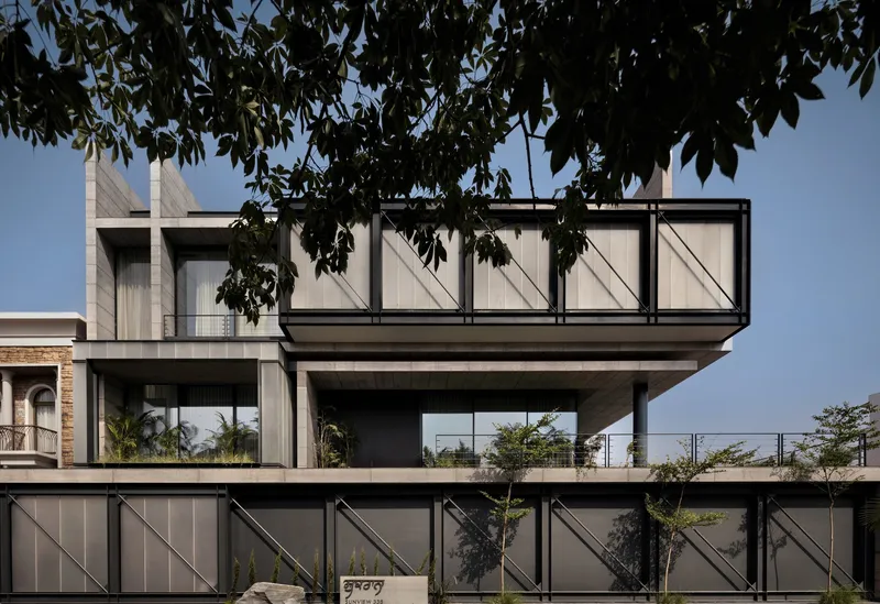 Street view of the cantilevered concrete volume with diagonal braced glazing panels framed by overhanging tree branches