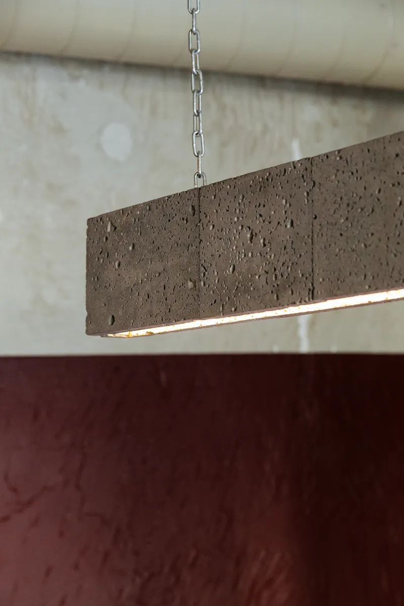 Suspended rectangular pendant light fixture in textured brown concrete with integrated linear illumination