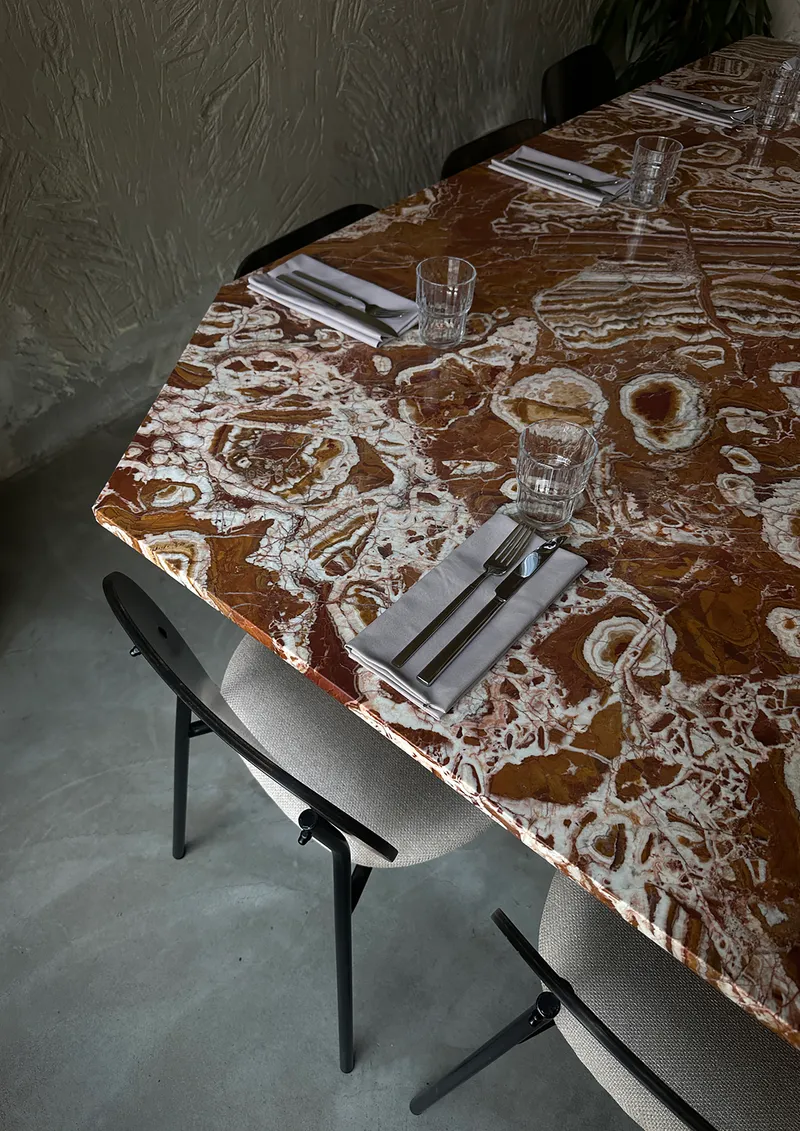 Overhead view of marbled stone dining table with organic white veining set for service