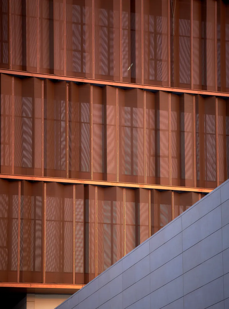 Close-up of the copper vertical fins with palm tree shadows reflected on the translucent panels