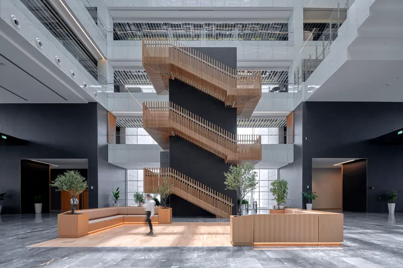 Ground-level lobby with timber-clad monumental stair cascading through the atrium and planters with trees
