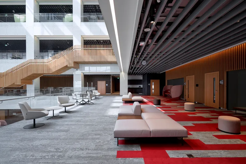 Ground floor lounge with modular seating on red and grey carpet beneath suspended walkways