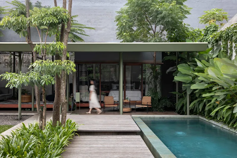 Timber deck terrace beside the pool with a figure walking beneath the flat roof overhang