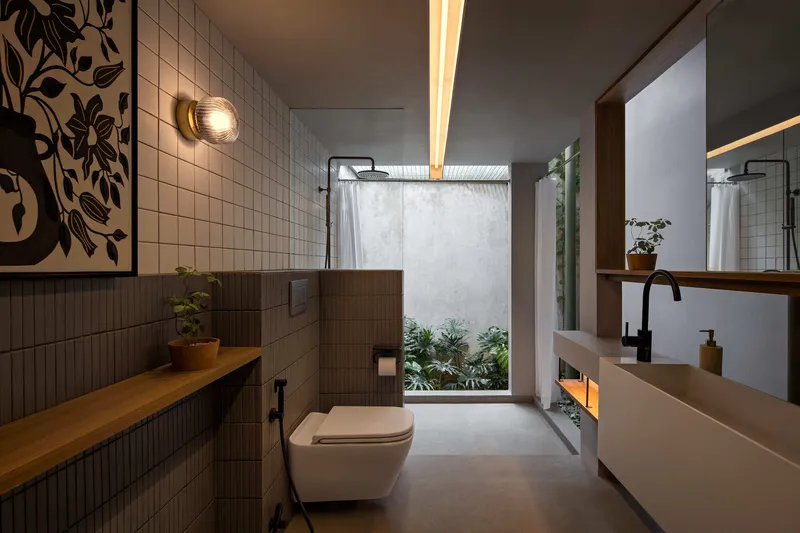 Bathroom with square tile walls and timber ledge opening to a small planted lightwell