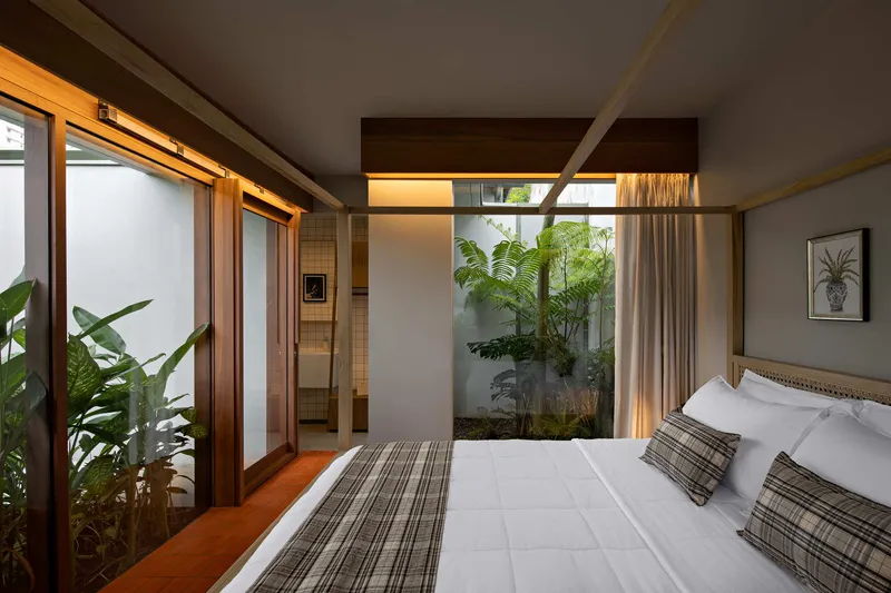 View across the bed toward a skylit internal garden with ferns framed by timber beams