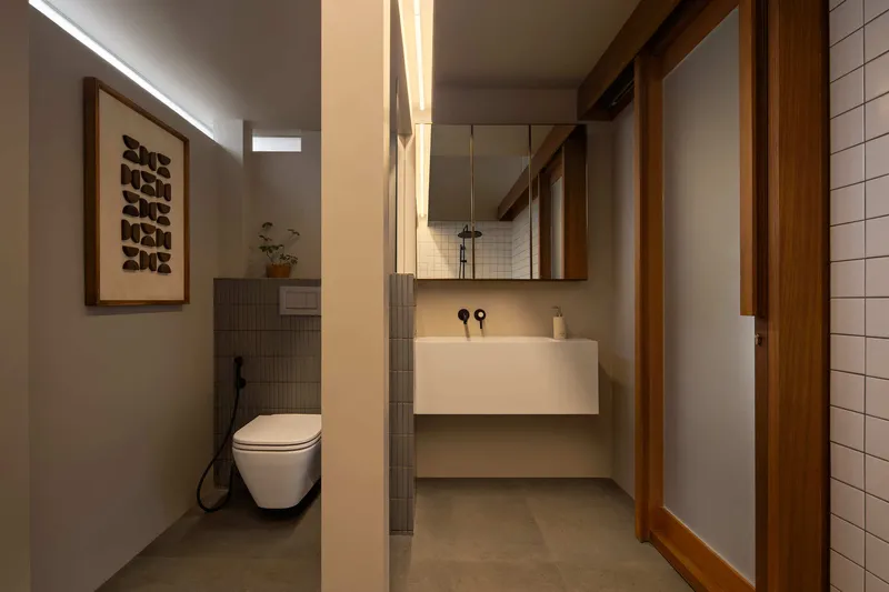 Bathroom with floating vanity, timber framed mirror and vertical strip lighting along the partition wall