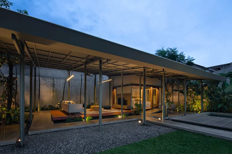 Exterior view of the low-slung roof canopy over glazed walls at dusk with perimeter planting