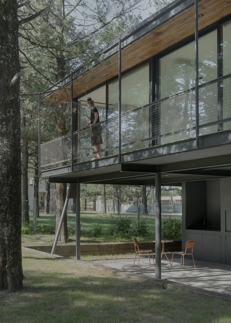 Figure descending exterior staircase with wire mesh railing beneath timber soffit and glass walls