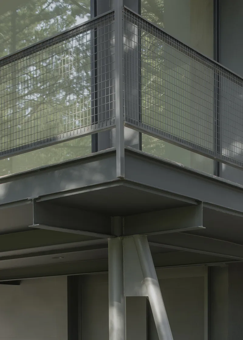 Detail of steel column junction supporting wire mesh balcony and cantilevered upper floor