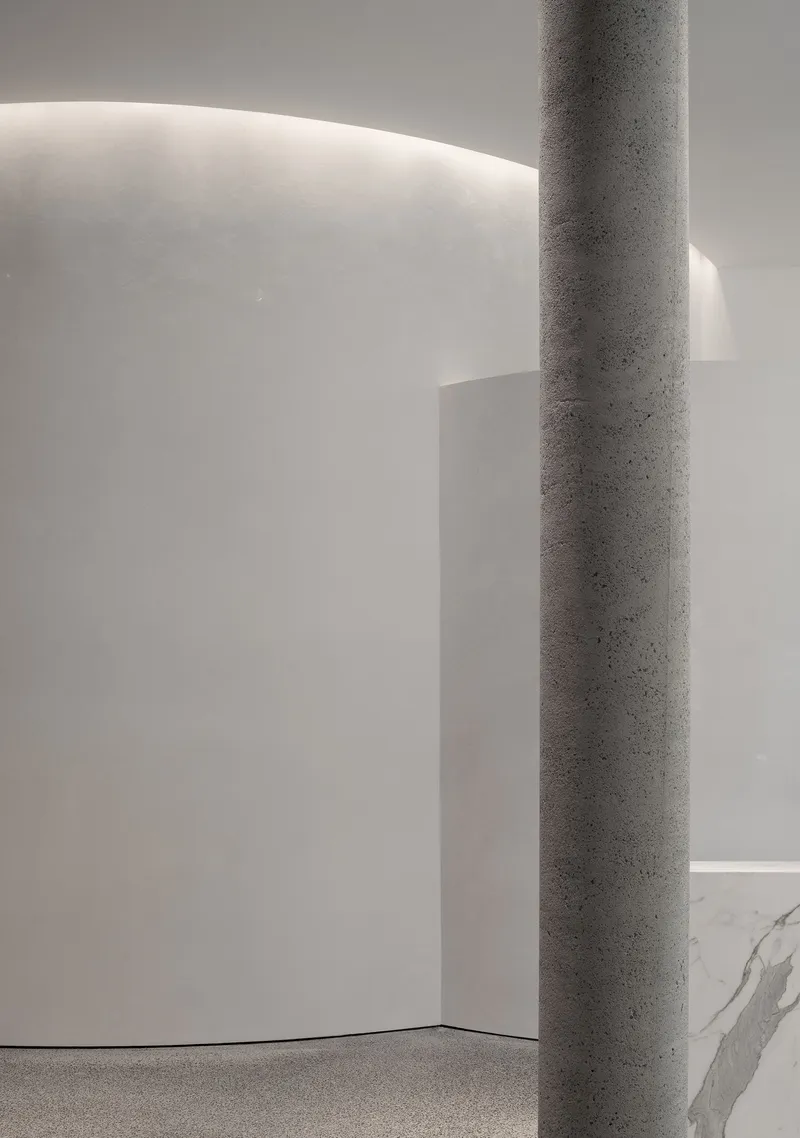 Detail of a terrazzo column against a curved white wall with cove lighting washing the surface