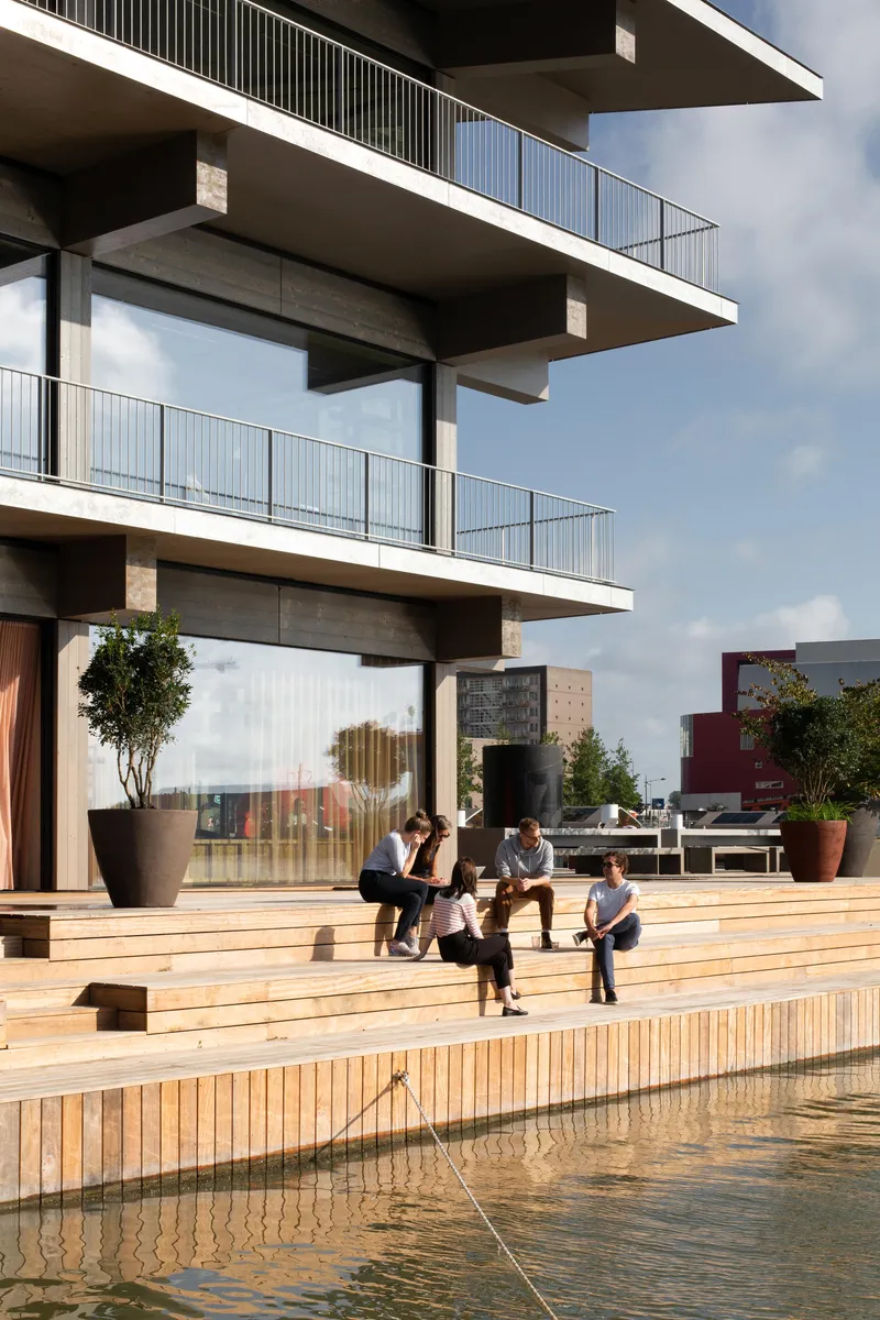 Timber deck terrace with people seated as the water edge meets the floating platform