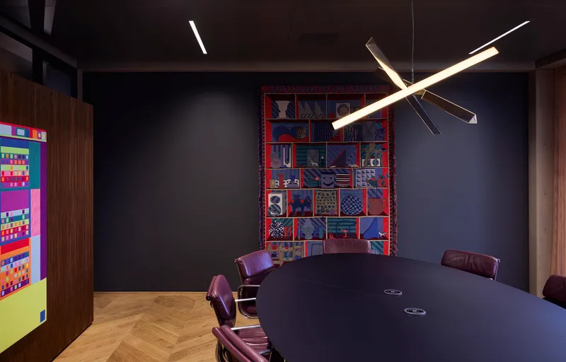Conference room with dark walls and a suspended linear light fixture above a round table