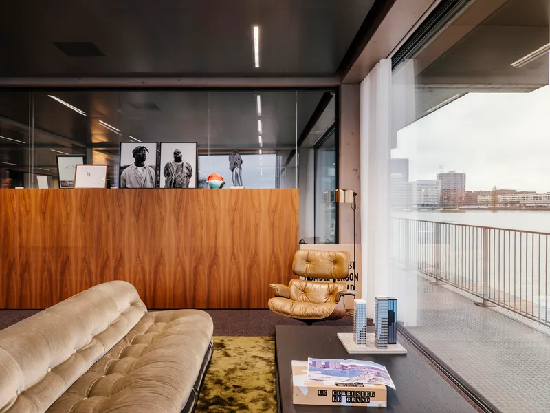 Living space with walnut veneer partition and glass walls opening to a terrace overlooking the water