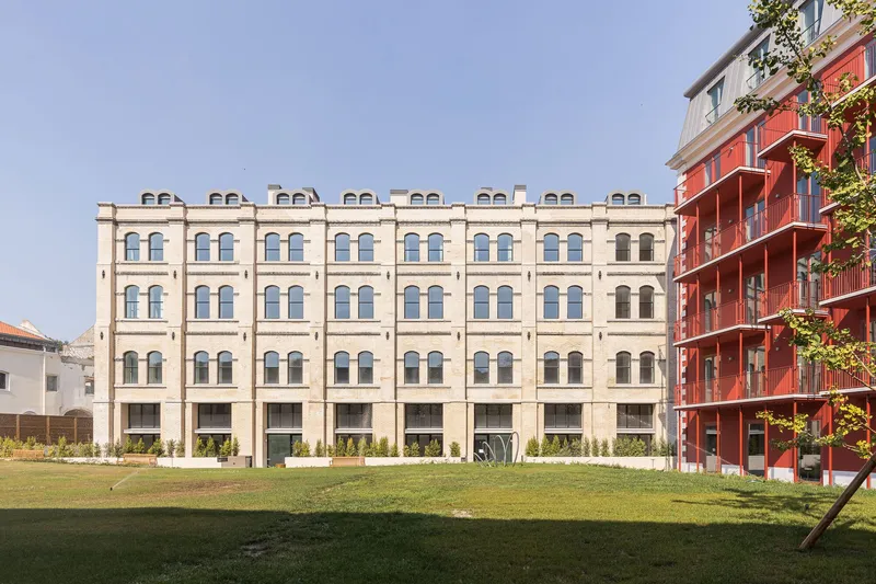 Courtyard view showing the cream masonry facade with paired arched windows and planted lawn