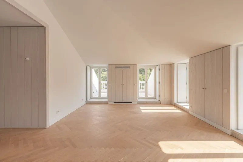 Room with sloped ceiling and light wood built-in cabinetry flanking central window