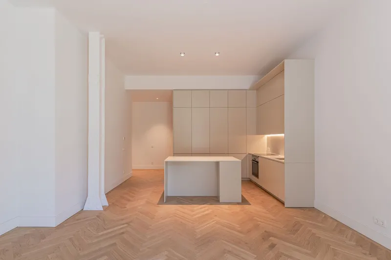 Compact kitchen with island and recessed lighting beneath dropped ceiling and herringbone oak flooring