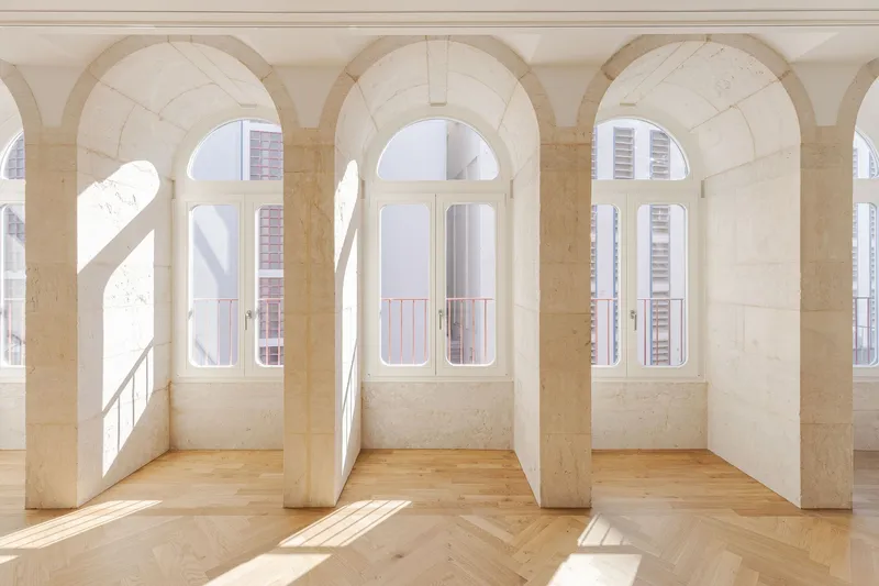 Interior room with stone arched openings and herringbone oak flooring in bright morning sunlight