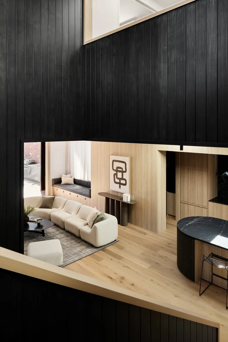 Mezzanine view overlooking the living room with timber joinery and black vertical timber-clad walls