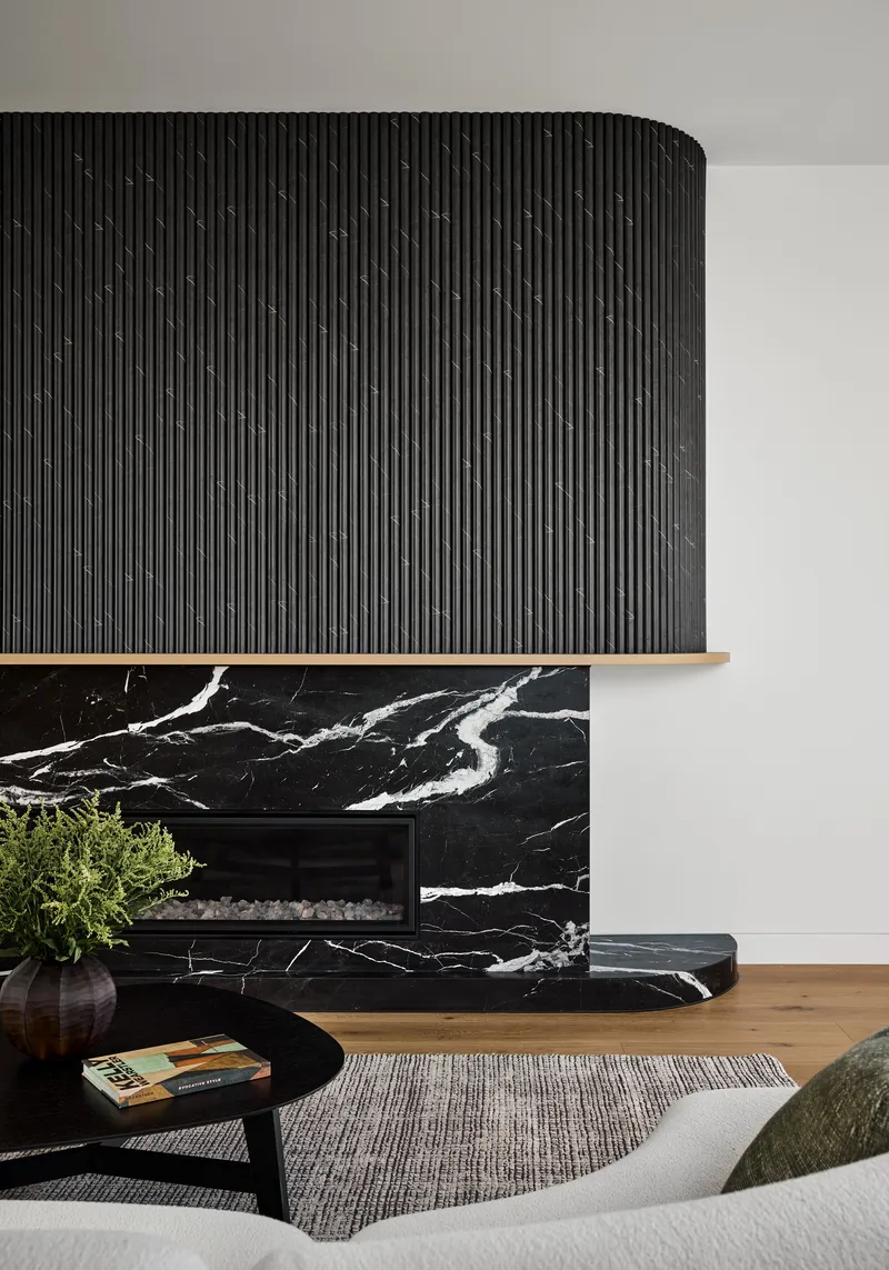 Close-up of the black marble fireplace hearth with veined stone and vertical timber surround above