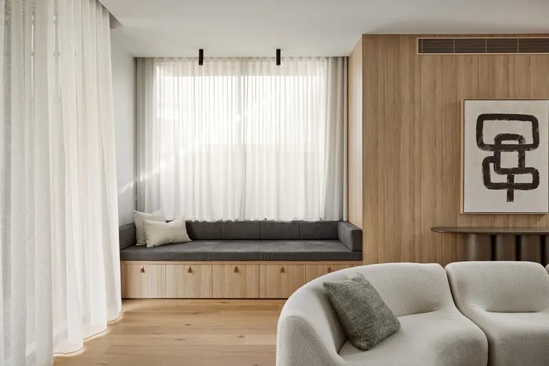 Built-in window seat with timber storage below and sheer curtains filtering soft natural light