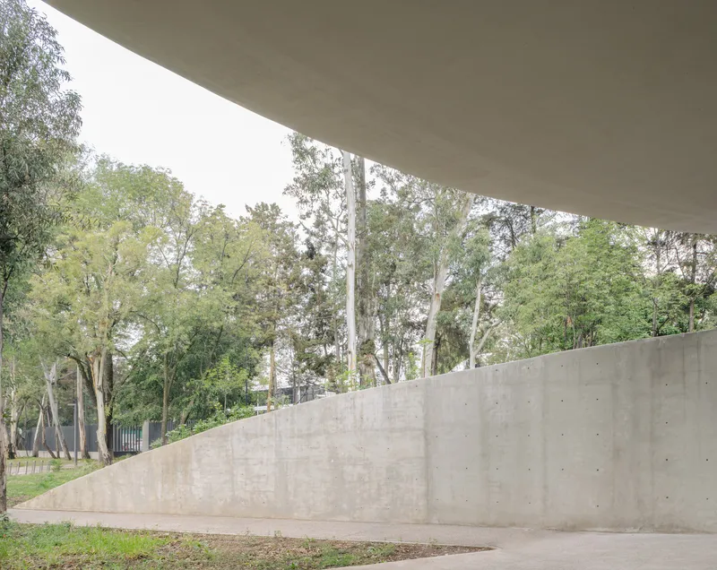 View from beneath the cantilevered concrete roof slab looking toward an angled concrete retaining wall