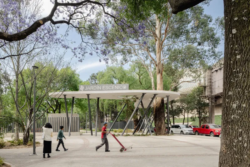 Entry canopy with angled steel supports sheltering visitors and parked cars beneath mature trees