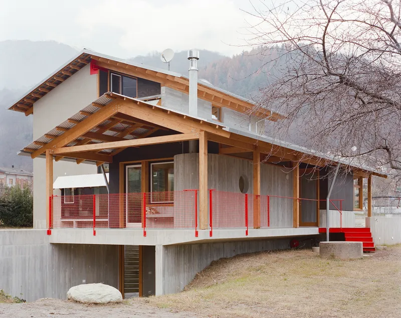 Elevated timber-framed porch with red mesh balustrade and corrugated metal skirting under bare tree branches