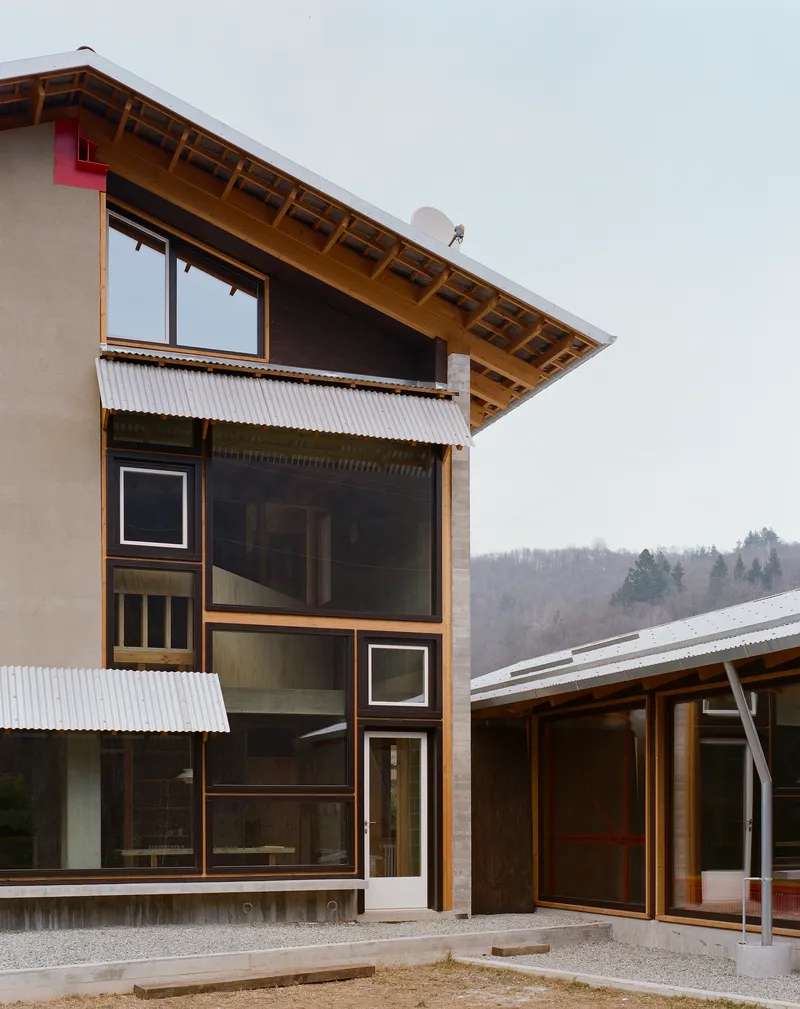 Corner facade with stacked windows and corrugated metal awnings beneath an overcast sky