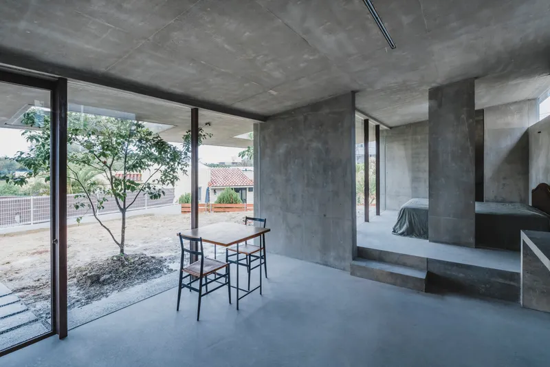 Concrete interior with smooth floor, exposed ceiling beams, and a small tree planted inside