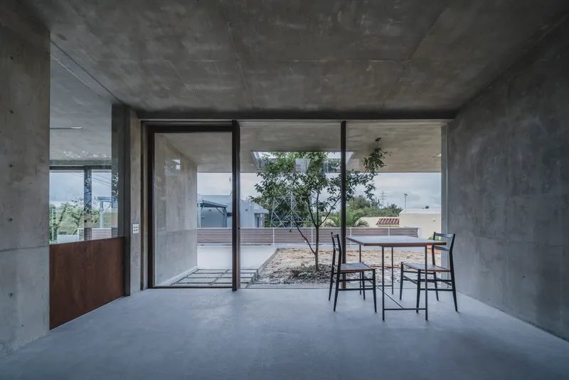 Living space with sliding glass doors framing view of interior courtyard with planted tree